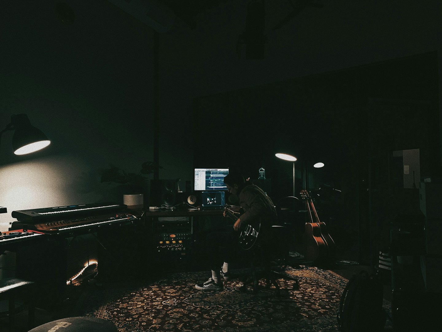 Musician sits at a desk producing music on computer monitors.