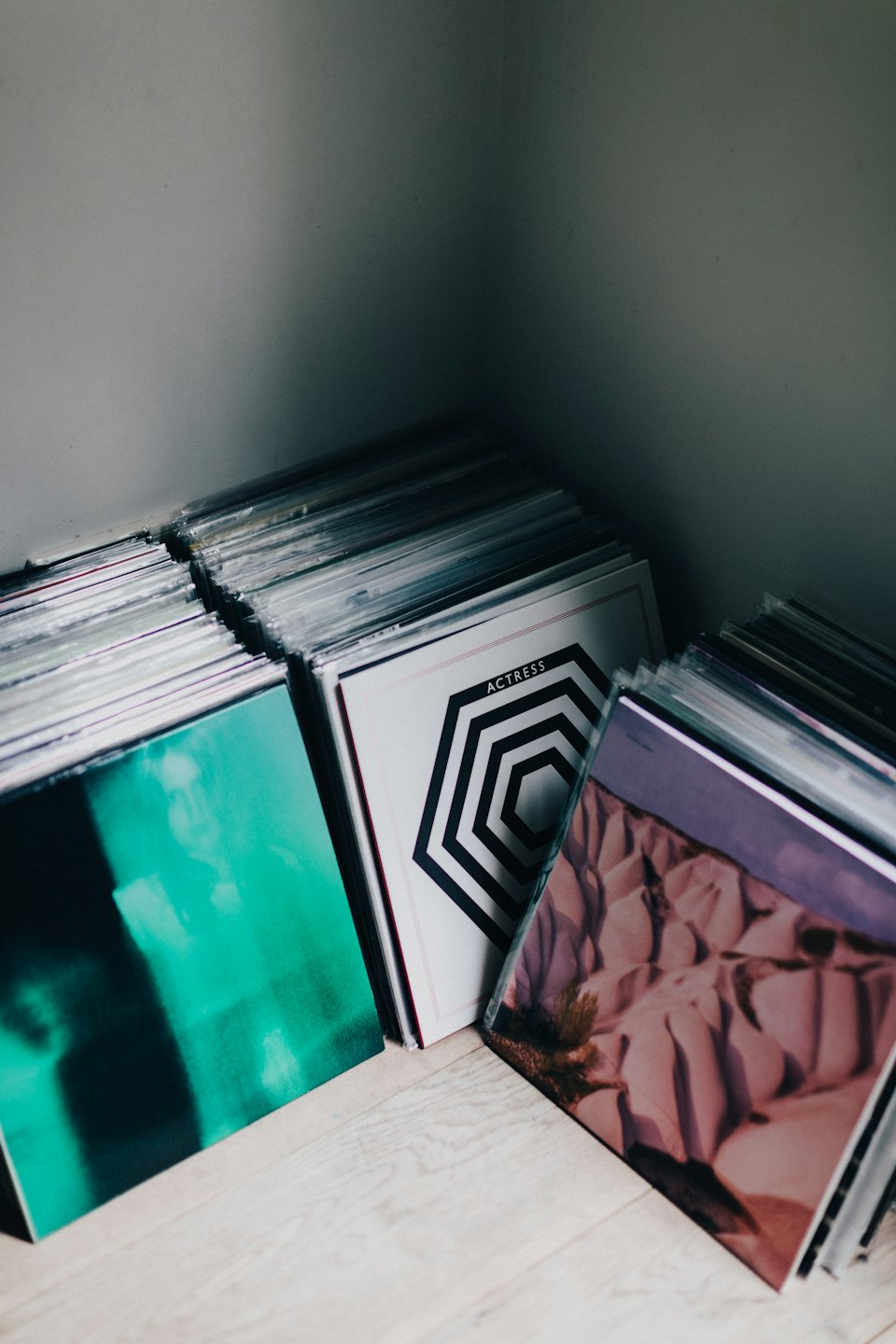 Stacks of vinyl records arranged on a light wooden floor.